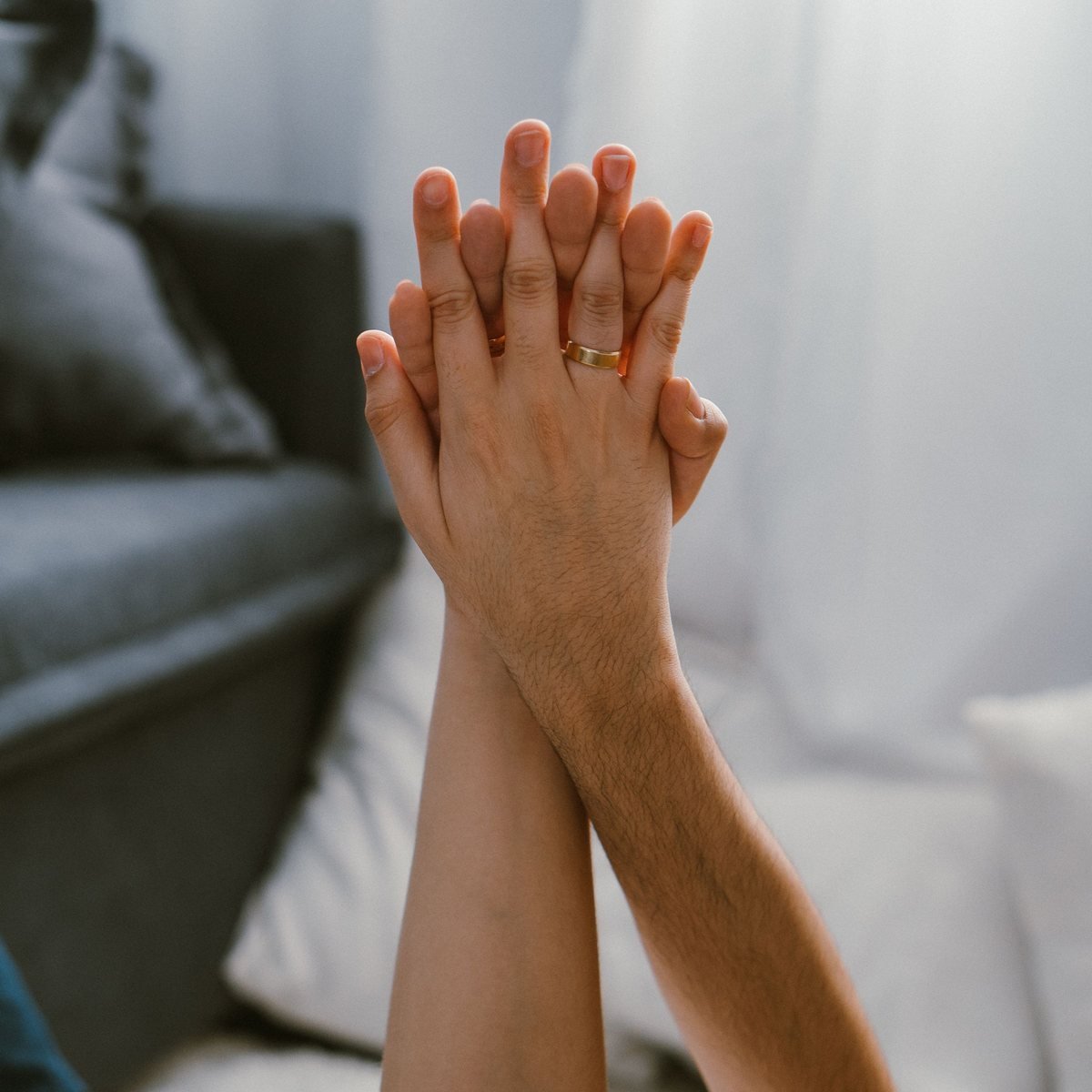Two hands raised and pressed together, palm to palm, in a bright room